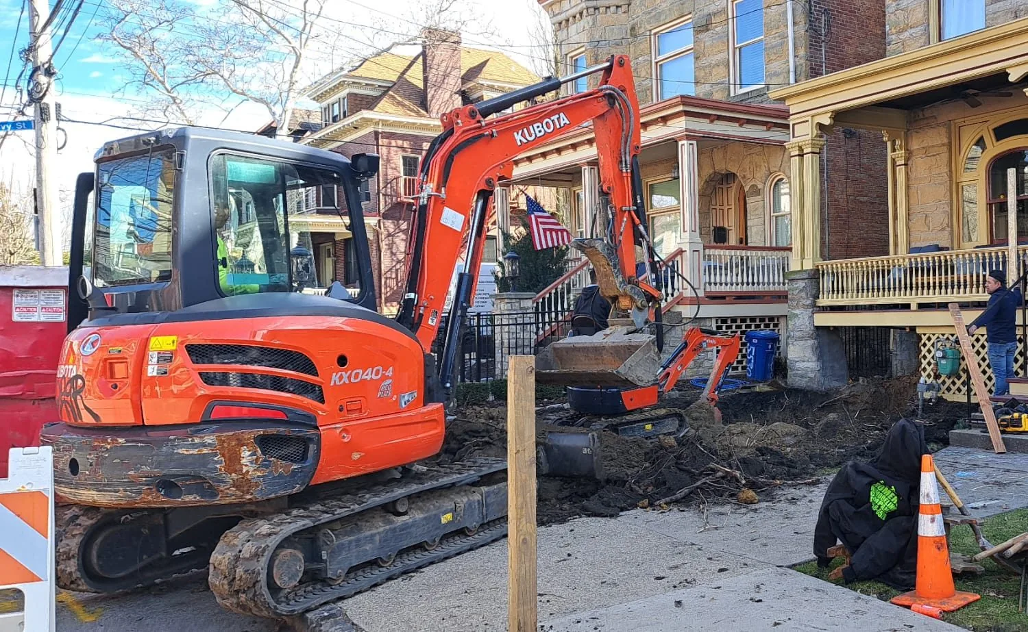 An excavator working in front of a row of Pittsburgh houses