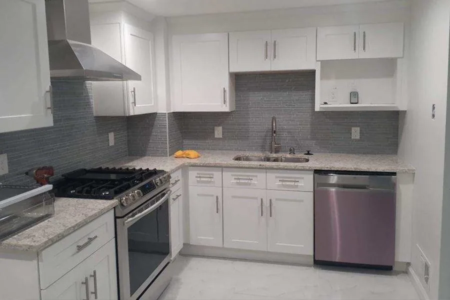 A finished kitchen with white cabinets and a tile backsplash